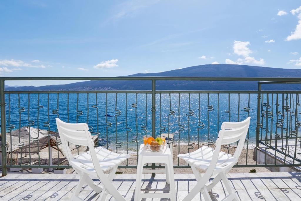 two chairs and a table on a balcony overlooking the water at Rosic Apartments Baosici in Bao&scaron;ići