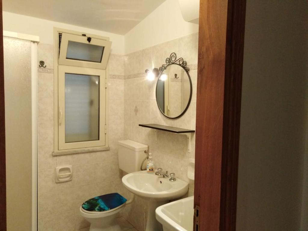 W łazience znajduje się umywalka, toaleta i lustro. w obiekcie Casa Natura sotto il Castello w mieście Castelbuono