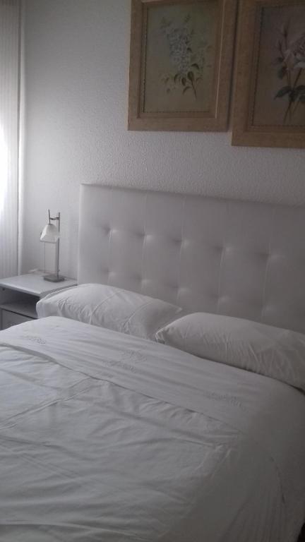 a bedroom with two white beds and a lamp at Pensión Room Pamplona in Pamplona