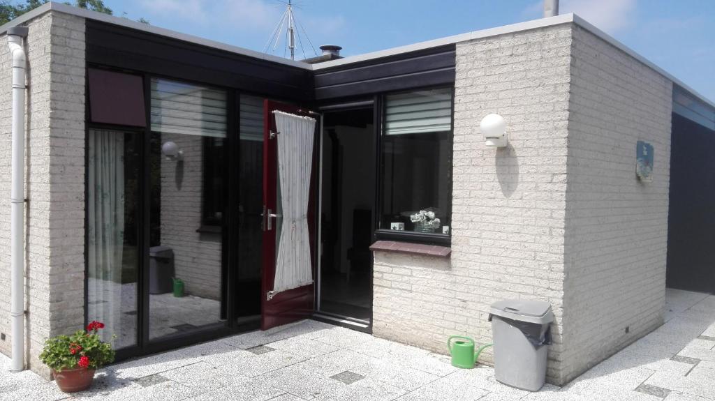 ein weißes Backsteingebäude mit einer Tür und einem Fenster in der Unterkunft Klepperstee Esdoorn 3 in Ouddorp