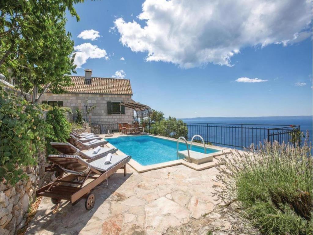a house with a swimming pool with chairs and the ocean at Holiday House Brela in Brela