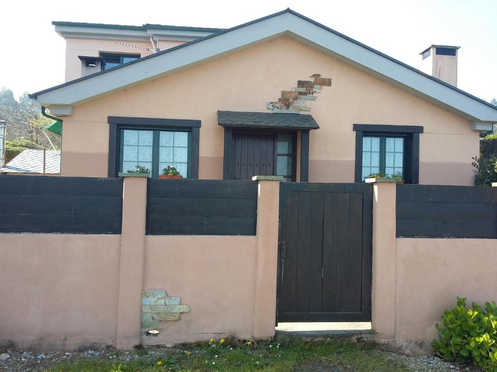 una casa con una puerta negra y una valla en Casita de Folgosa, en Ribadeo
