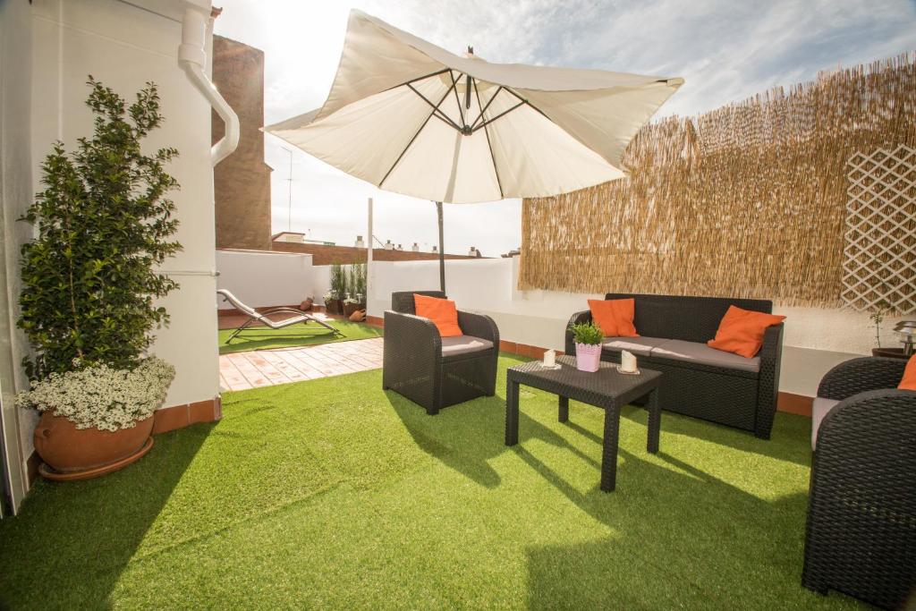 a patio with chairs and an umbrella and grass at Ático Azahar in Córdoba