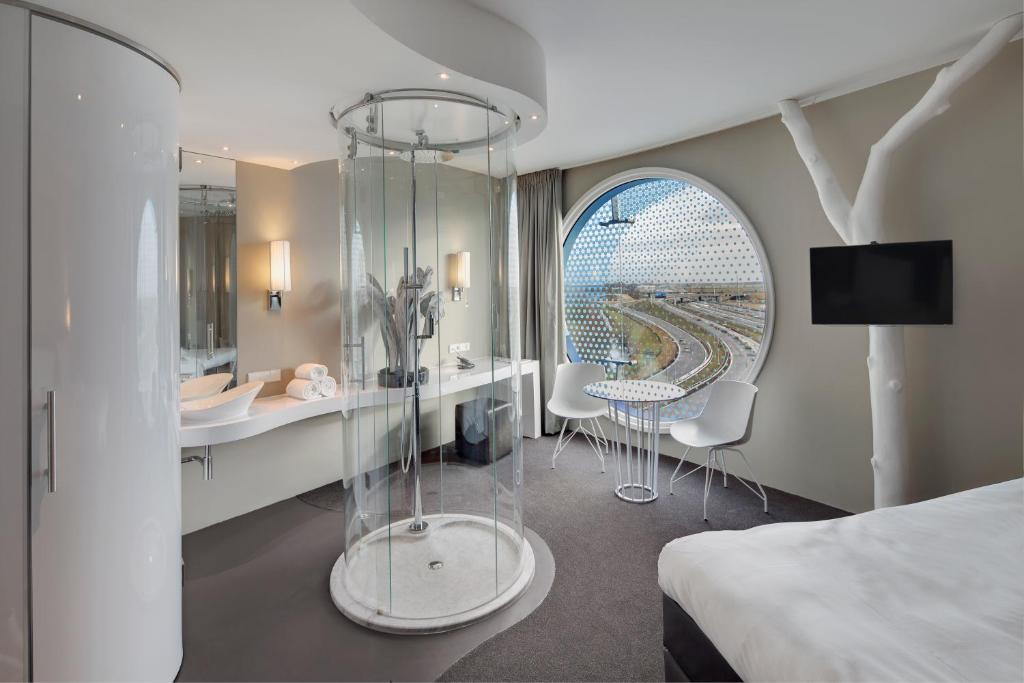アムステルダムにあるフレッチャー ホテル アムステルダムのベッド、テーブル、椅子が備わるホテルルームです。