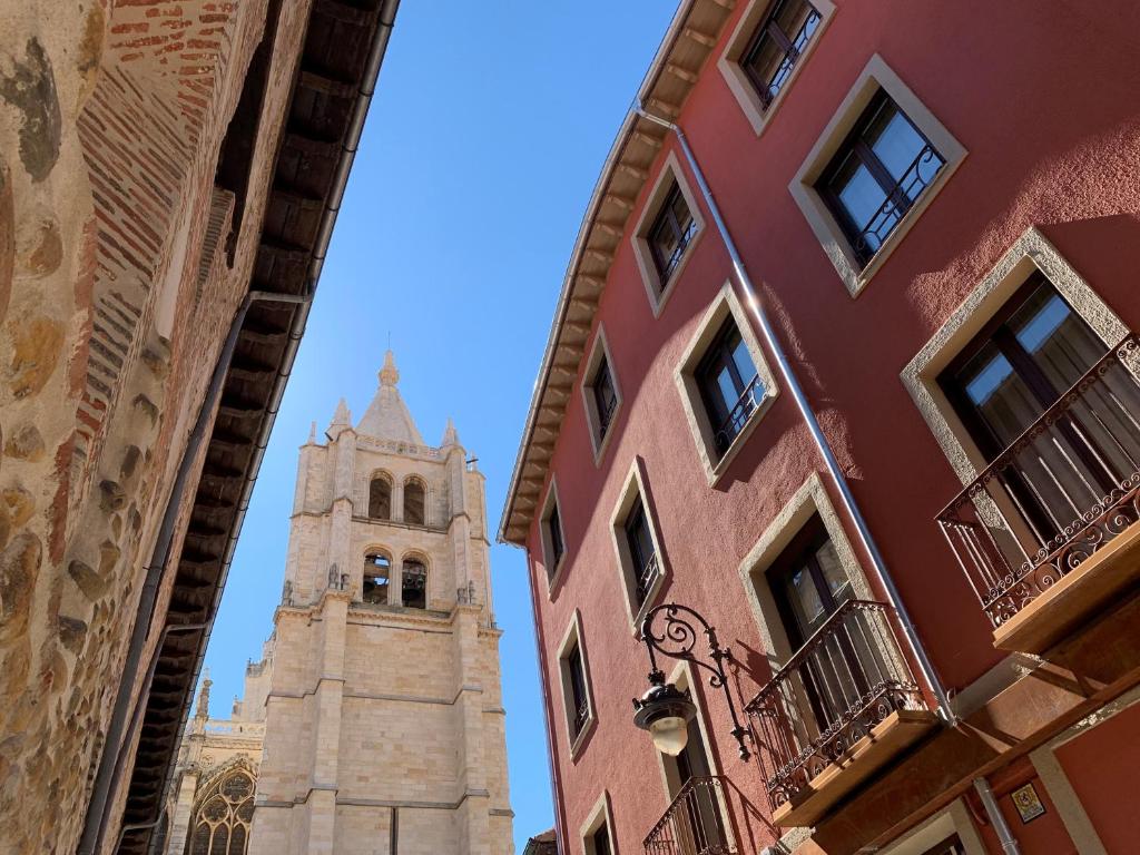 una torre del reloj alta en medio de dos edificios en Apartamentos m.bell, en León