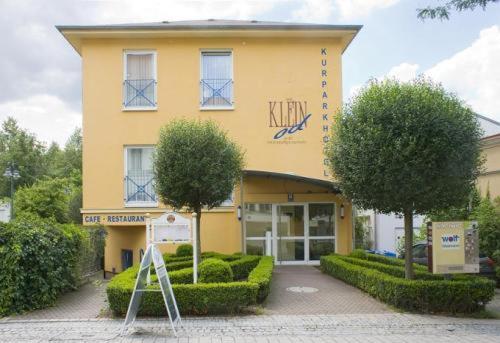 ein gelbes Gebäude mit einem Schild davor in der Unterkunft Kurparkhotel Das Kleinod in Bad Kissingen