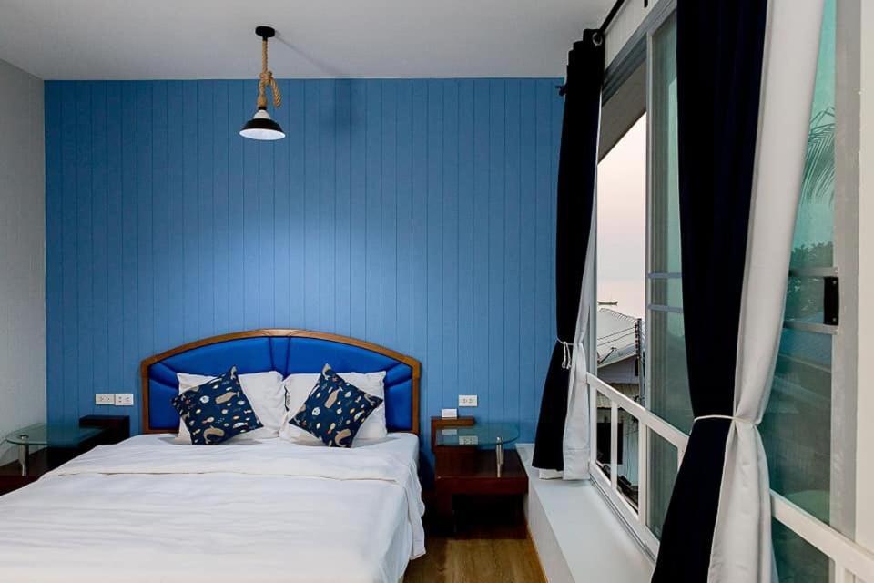 a bedroom with a blue wall and a bed with pillows at Chill Days @ Koh Larn in Ko Larn