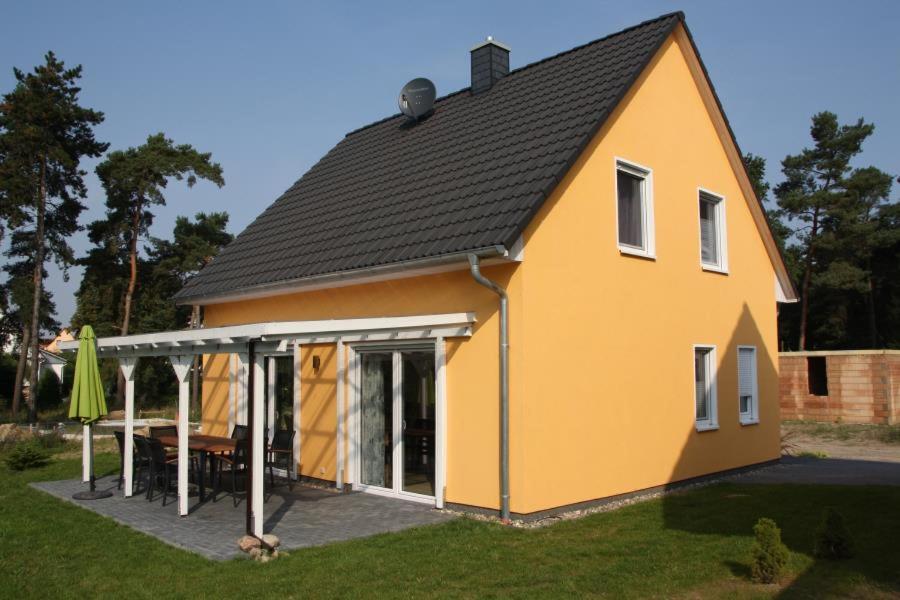 a yellow house with a table in a yard at K 99 - Ferienhaus mit Kamin & WLAN in Röbel an der Müritz in Röbel