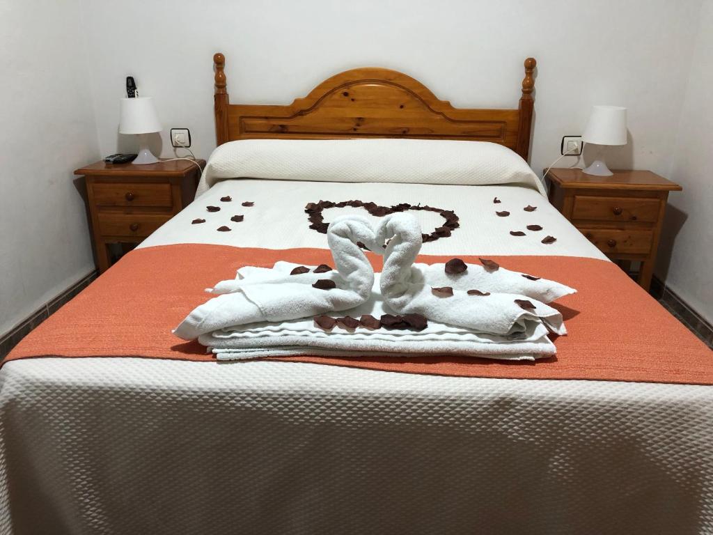 Una cama con mantas blancas y toallas. en Hostal Restaurante Taibilla, en Nerpio