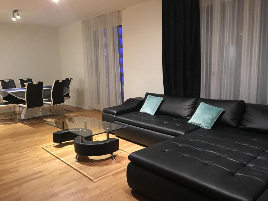 a living room with a black leather couch and a table at Cocoon 77 Apartments in Stuttgart