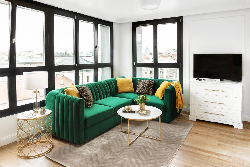 un sofá verde en una sala de estar con ventanas en Apartament Golden Place 2, en Cracovia