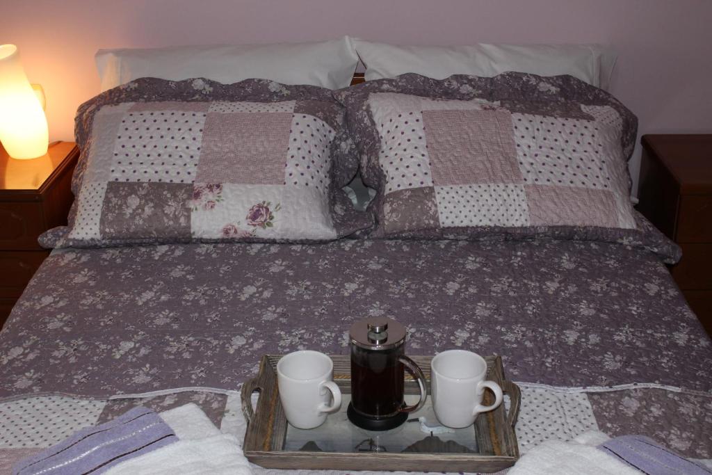 Una cama con una bandeja con dos tazas y tazas. en SOUZANA ROOMS 1, en Nea Plagia