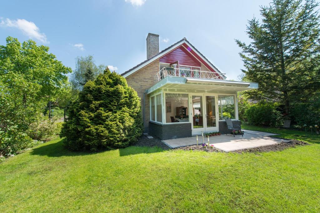 a house with a porch on a green lawn at Bed and Breakfast Hoorn in Hoorn