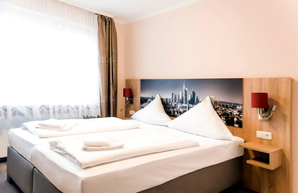 a bedroom with a large white bed with a window at Hotel Royal in Frankfurt/Main