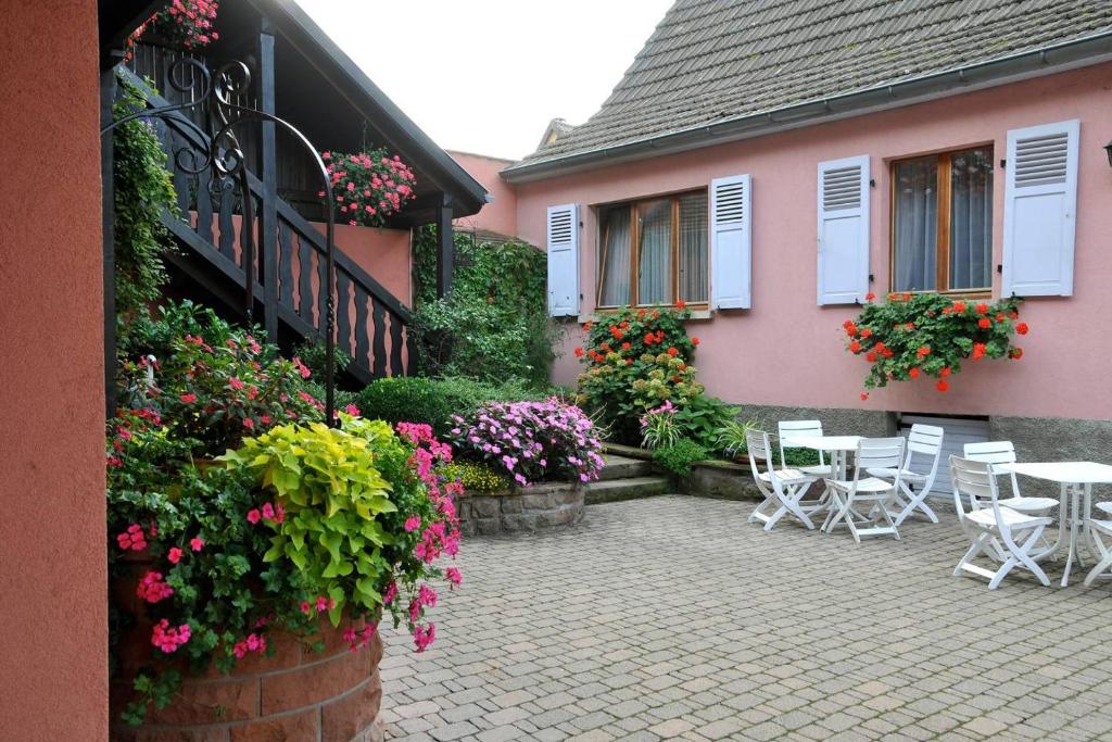une terrasse avec des chaises et des fleurs devant une maison dans l'établissement Gite Weyer n°3, à Bergheim