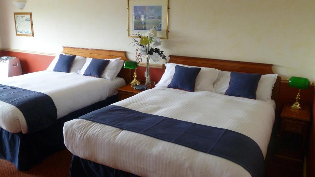 a hotel room with two beds with blue and white sheets at London Beach Country Hotel & Golf Club in Tenterden