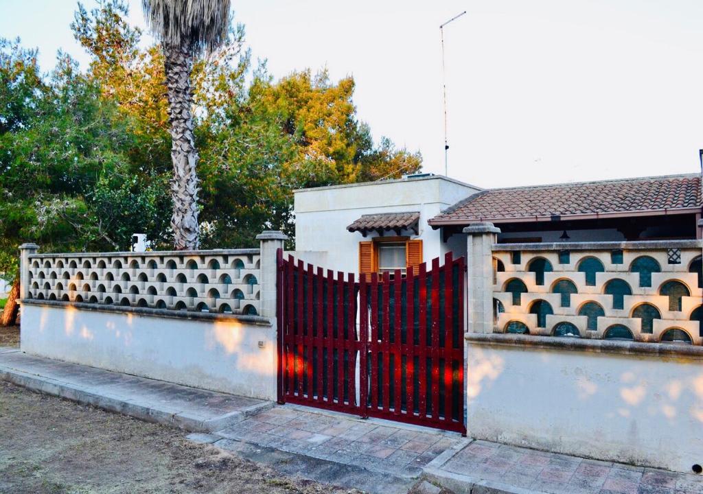 een hek met een rode poort voor een huis bij Villetta M&M a Torre dell'Orso in Torre dell'Orso