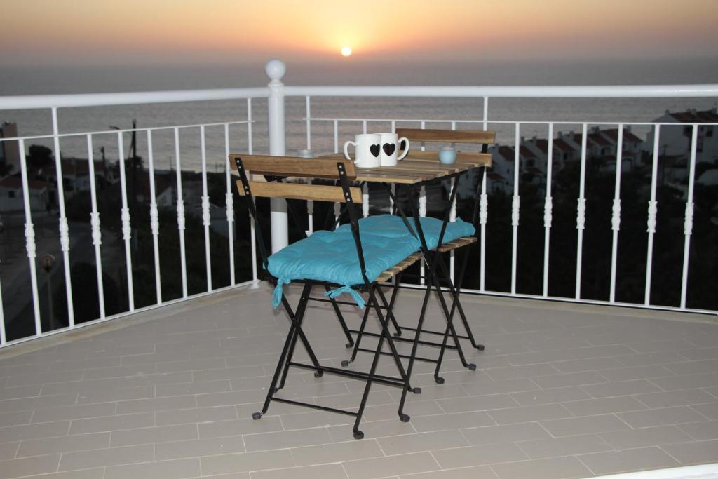 Ericeira Sunset Apartment في إيريسييرا: طاولة وكرسي على شرفة مع المحيط