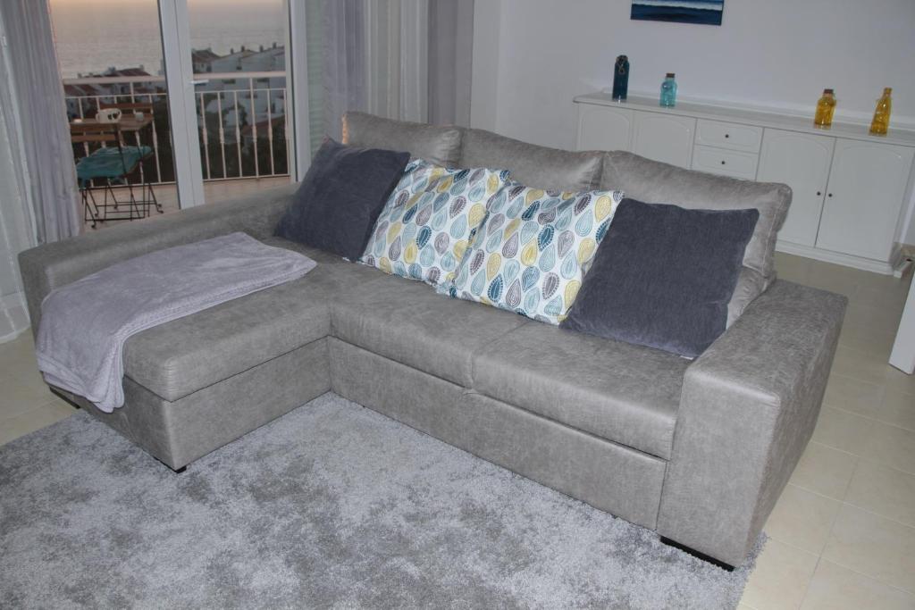 a living room with a gray couch with pillows at Ericeira Sunset Apartment in Ericeira