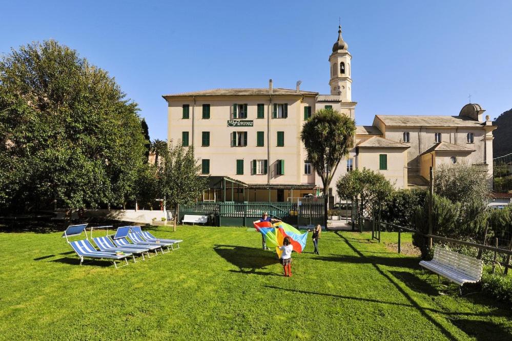 un bambino che tiene un ombrellone in un parco con sedie e un edificio di Hotel Florenz a Finale Ligure