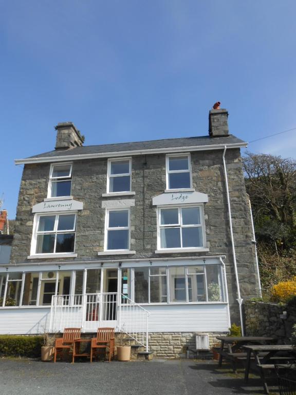 una gran casa de piedra con sillas delante en Lawrenny Lodge, en Barmouth