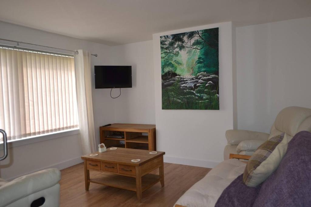 a living room with a couch and a table at Kirkside Holiday Home in Alness