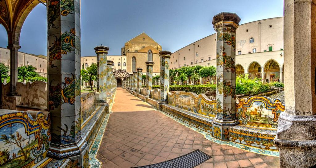 um pátio de um edifício com mosaicos nas colunas em Casa del Sole em Nápoles