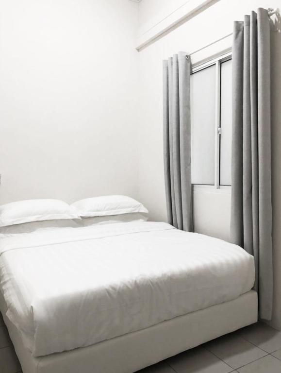 a white bedroom with a bed and a window at Ozzy Lodge Semporna in Semporna