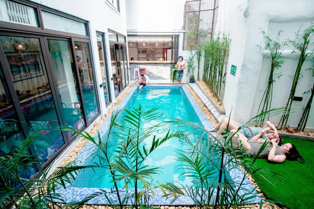 two women laying on the grass next to a swimming pool at Hanoi Buffalo Hostel in Hanoi