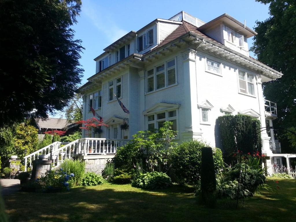 een groot wit huis met een veranda op een gazon bij Balfour House in Vancouver