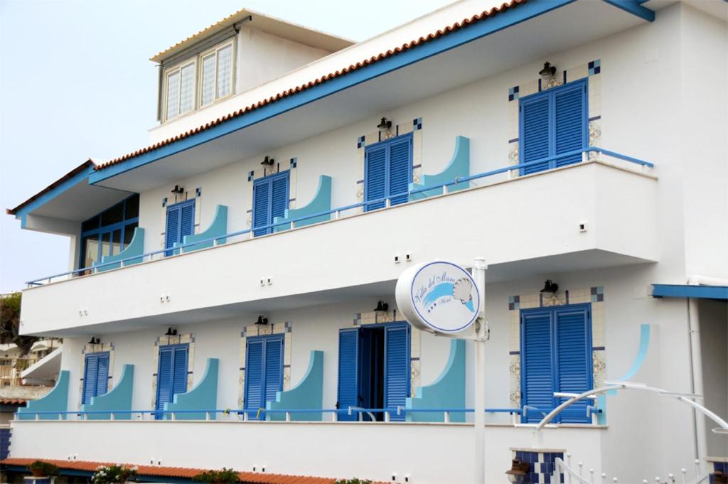 un edificio con persiane blu e un orologio sopra di Hotel Villa Del Mare a Bacoli