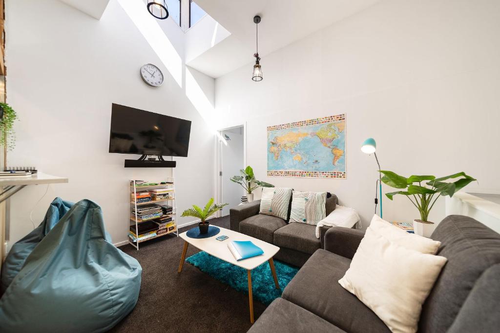 ein Wohnzimmer mit einem Sofa und einem Tisch in der Unterkunft Central, Modern Loft Style Home - 2 Min walk from Town in Queenstown