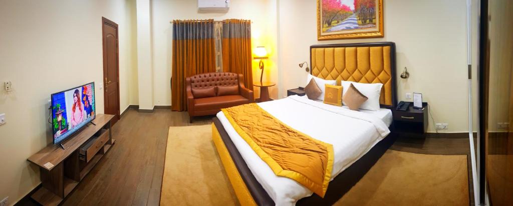 a hotel room with a large bed and a television at Hayyat Luxury Hotel Apartments in Lahore