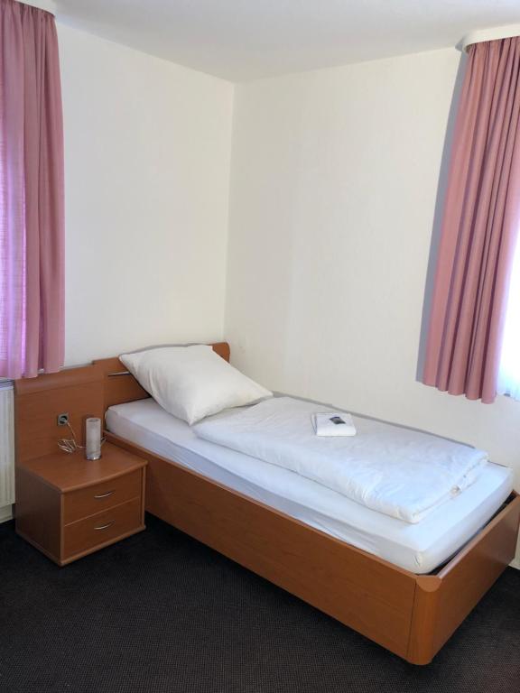 a small bed in a room with a night stand at Hotel Mivano Lehrte in Lehrte