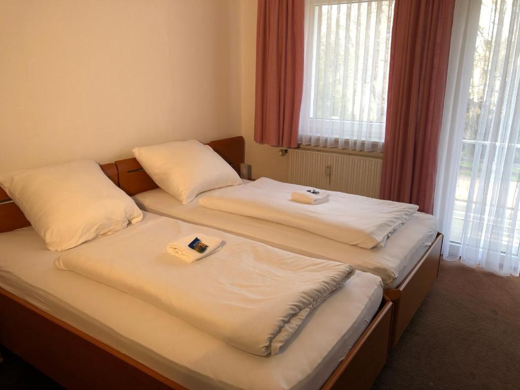 two twin beds in a room with a window at Hotel Mivano Lehrte in Lehrte