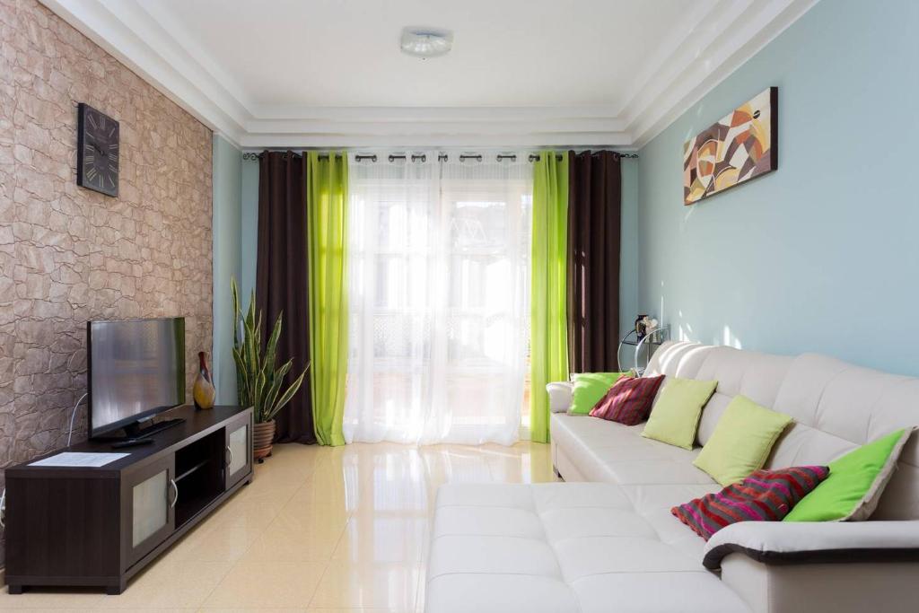 ein Wohnzimmer mit einem weißen Sofa und einem TV in der Unterkunft Orlando Apartment in Adeje