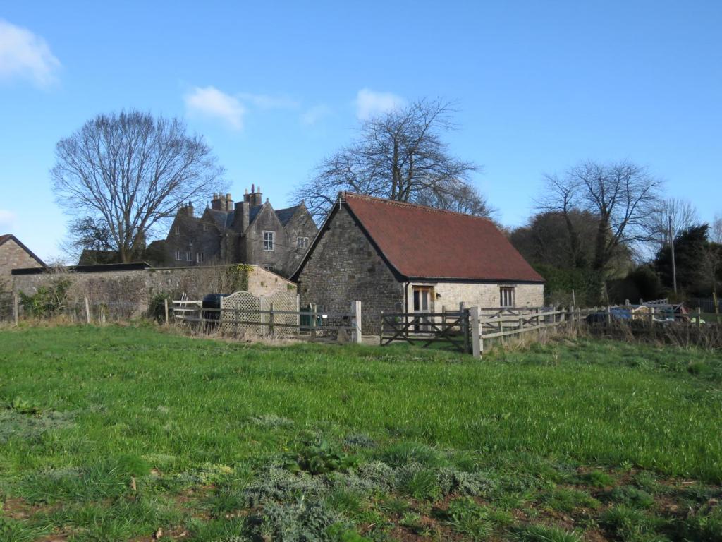 ein altes Steinhaus auf einem Feld mit einem Zaun in der Unterkunft Welsh Apple Barn in Chepstow