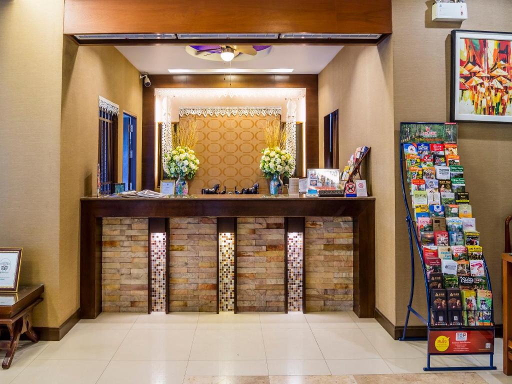 A compact reception desk is framed by floral arrangements and a rack of local brochures.