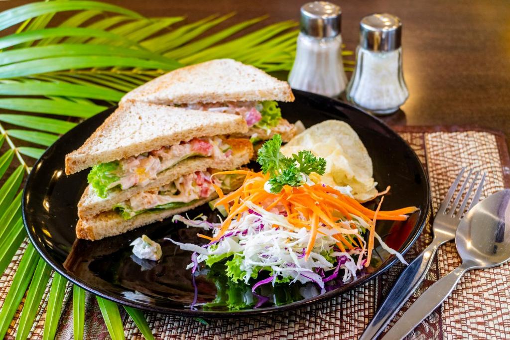 A toasted chicken sandwich served with crisps and shredded salad.
