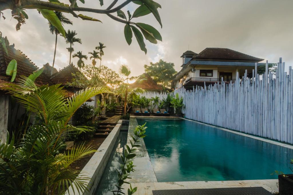 a swimming pool in front of a house with a fence at Green Taman Ubud by Prasi in Ubud