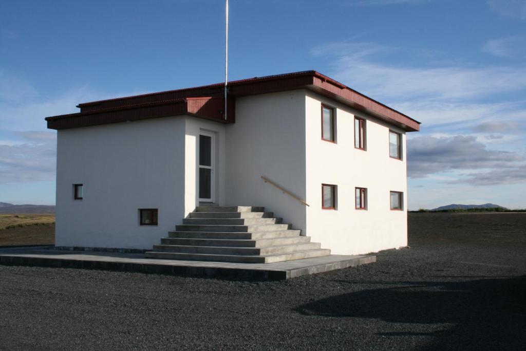 a white building with stairs in the middle of a field at Holssel road 864 in Myvatn