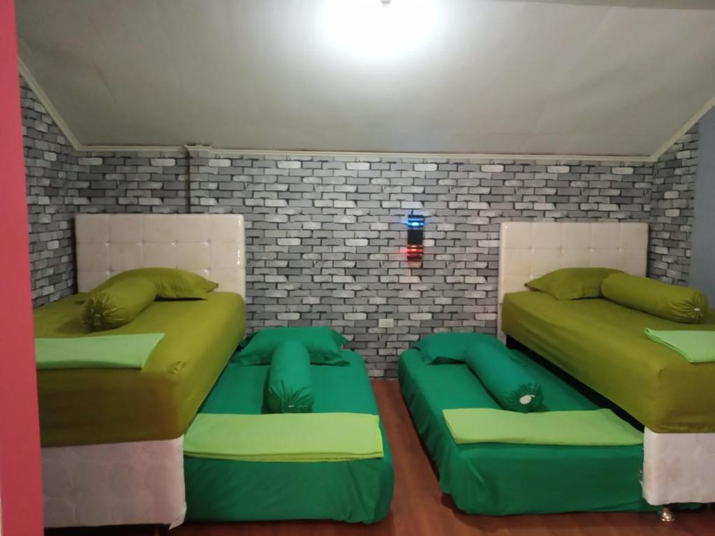 two beds with green pillows in a room at Pondok Oma in Lasikin