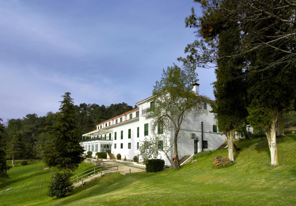 un gran edificio blanco en un exuberante campo verde en Parador de Cazorla, en Cazorla