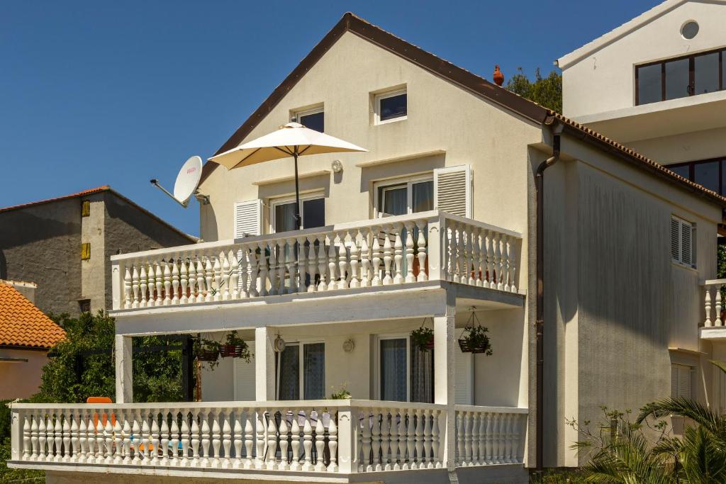 Casa blanca con balcón con sombrilla en Heimbring, en Rukavac