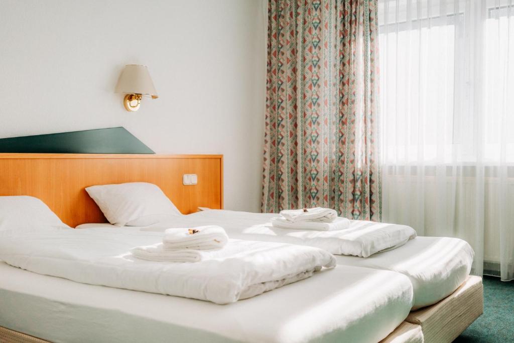 2 Betten in einem Hotelzimmer mit Handtüchern darauf in der Unterkunft Hotel Radau in Bad Harzburg