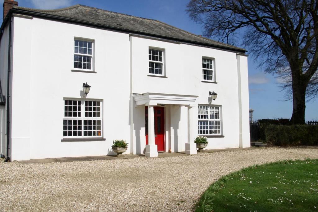 a white house with a red door at Ebberley Escapes in Great Torrington