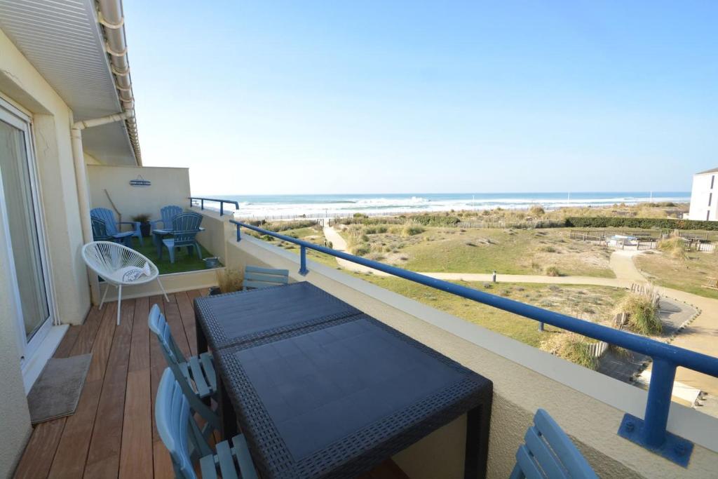 balcone con tavolo, sedie e spiaggia di APPT T3 Rêve d'Océan les pieds dans l'eau a Lacanau