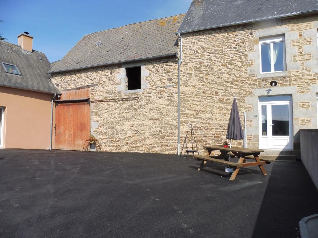 a patio with a table and an umbrella and a building at Gîte Le Desire in Tanis