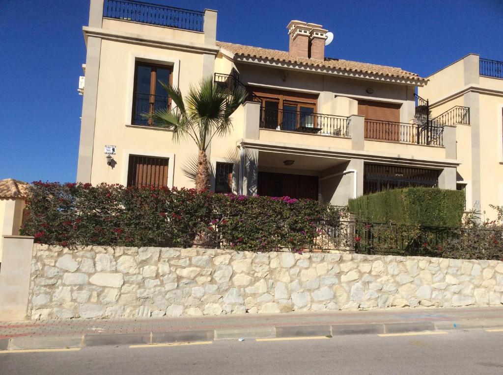 a white house with a palm tree and a stone wall at Casa de Nio in Algorfa