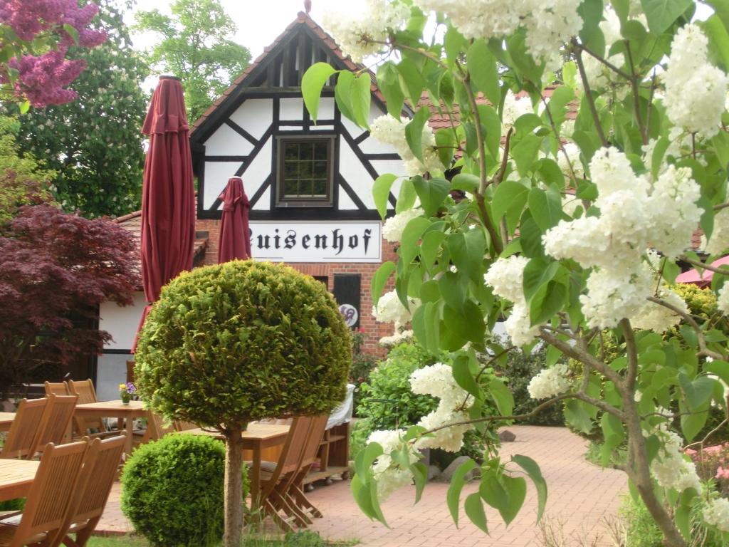 a building with tables and umbrellas in a garden at Luisenhof in Neuglobsow